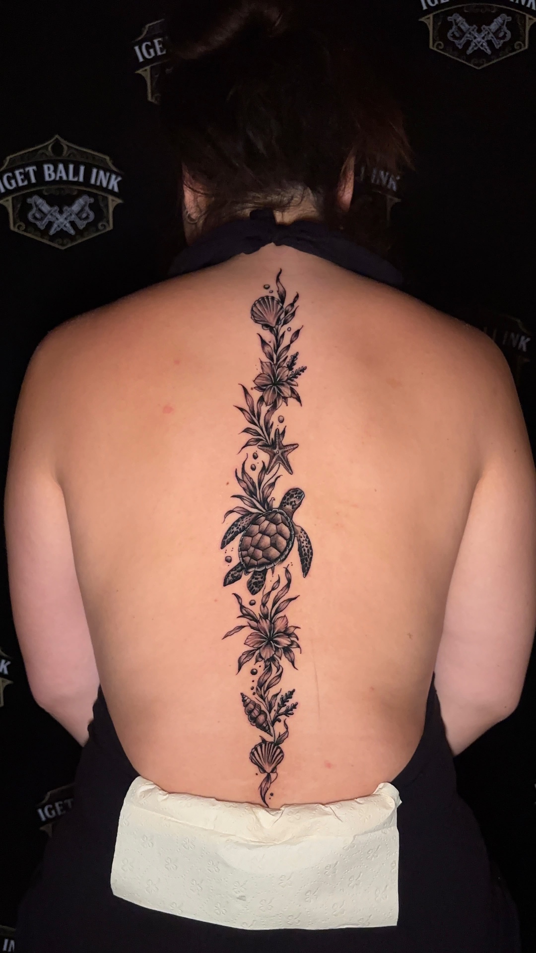 Fine line sea turtle and floral spine tattoo