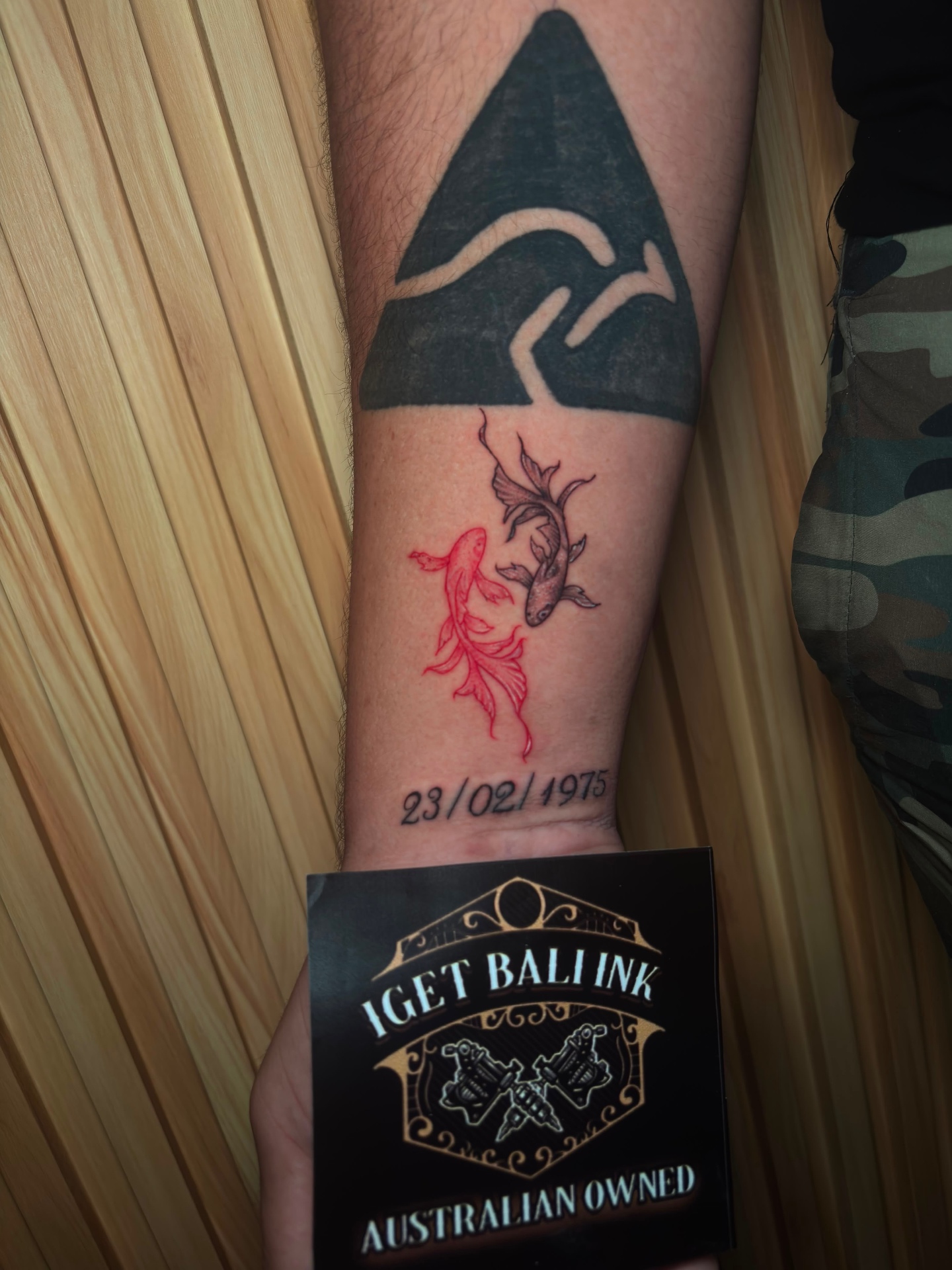 Red and black koi fish forearm tattoo with date lettering