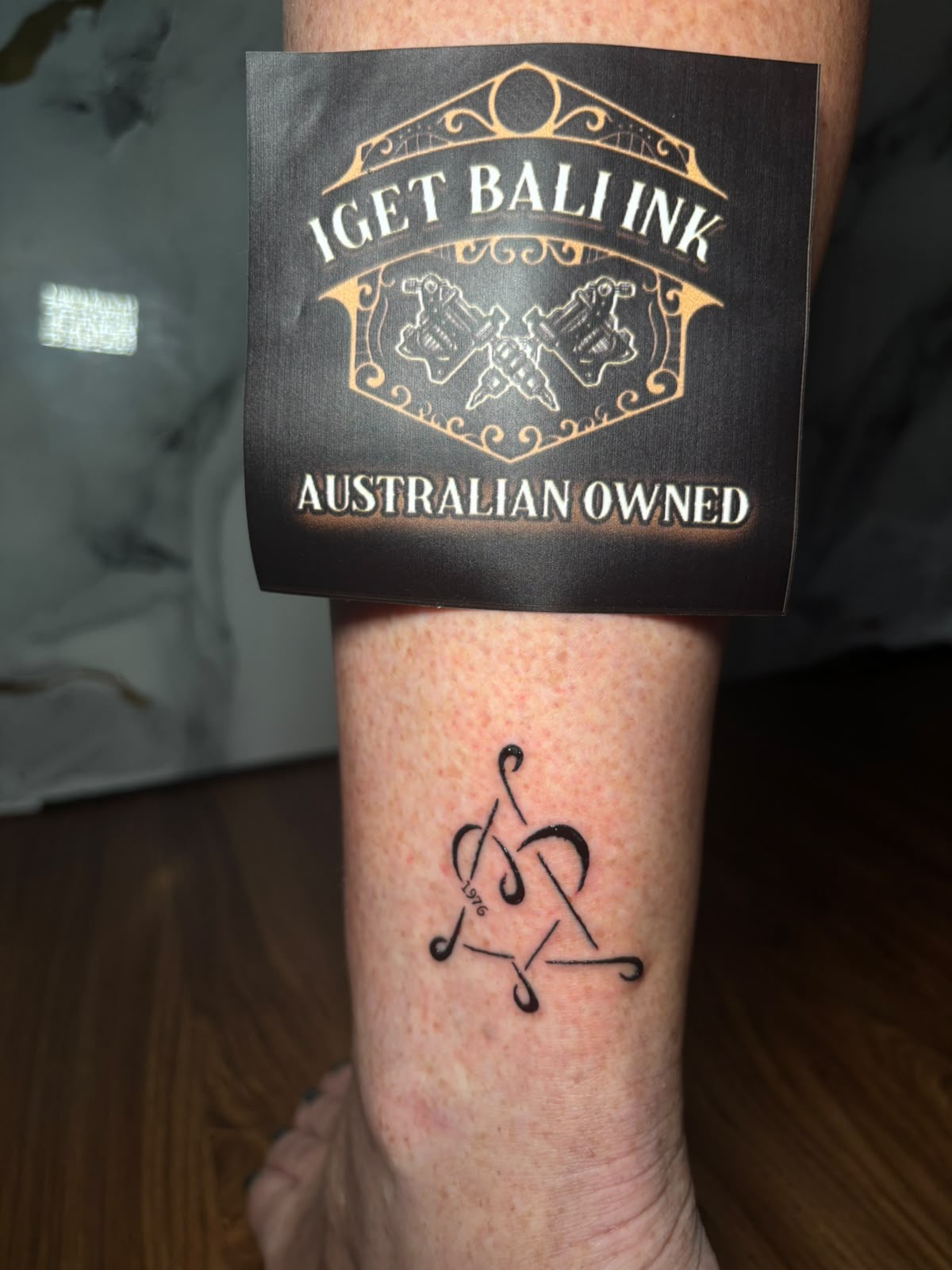 Fine line triquetra symbol with 1976 lettering on the ankle