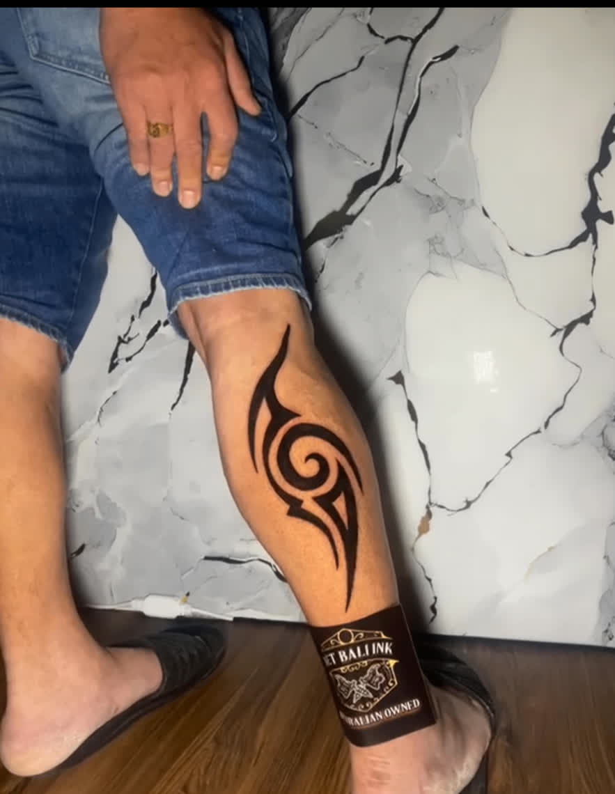 Bold tribal calf tattoo in solid black