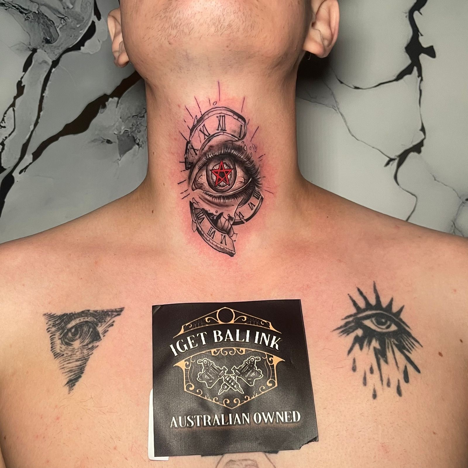 Realistic eye with clock and pentagram tattoo on the neck