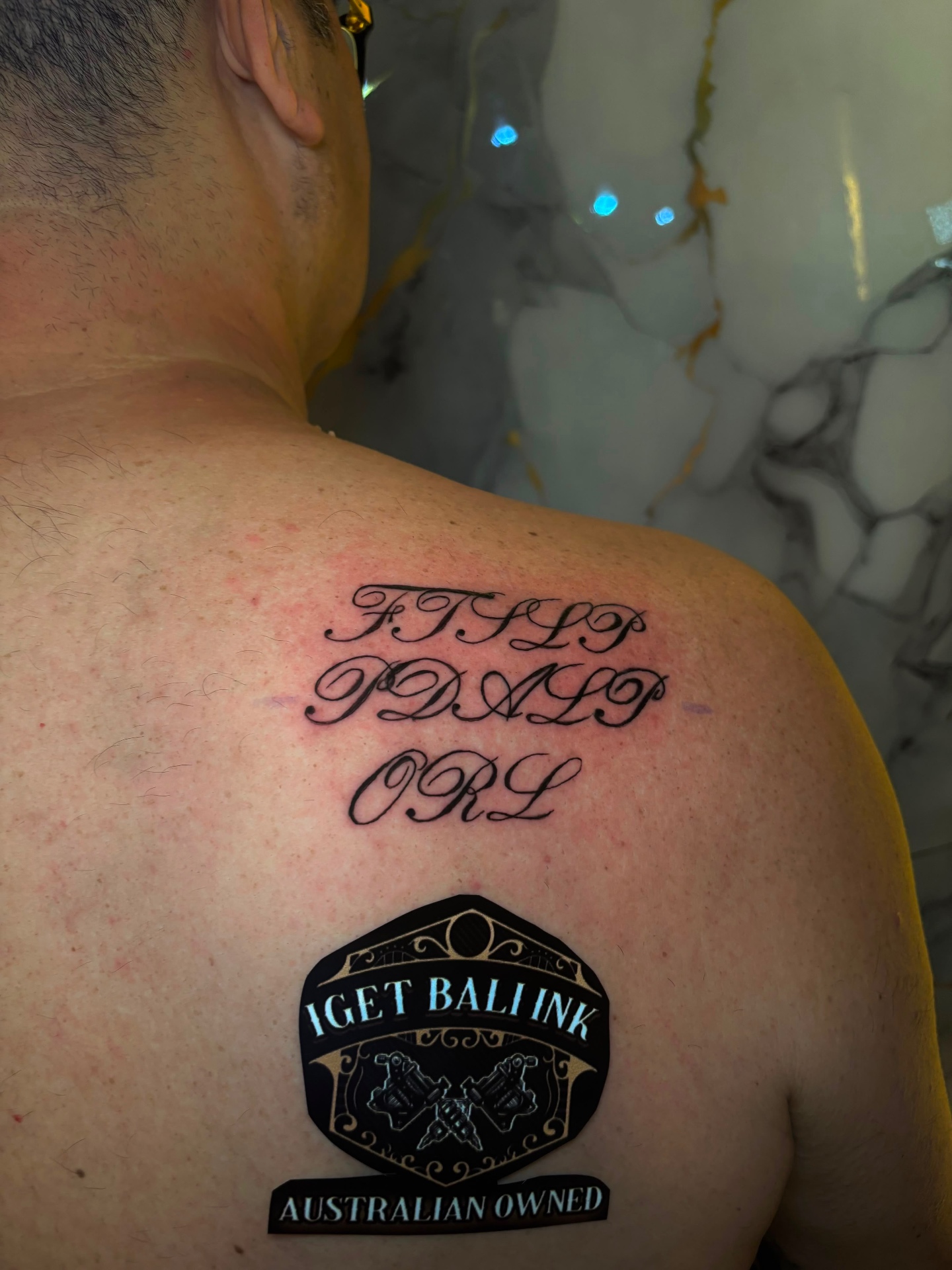 Script initials lettering on the shoulder blade