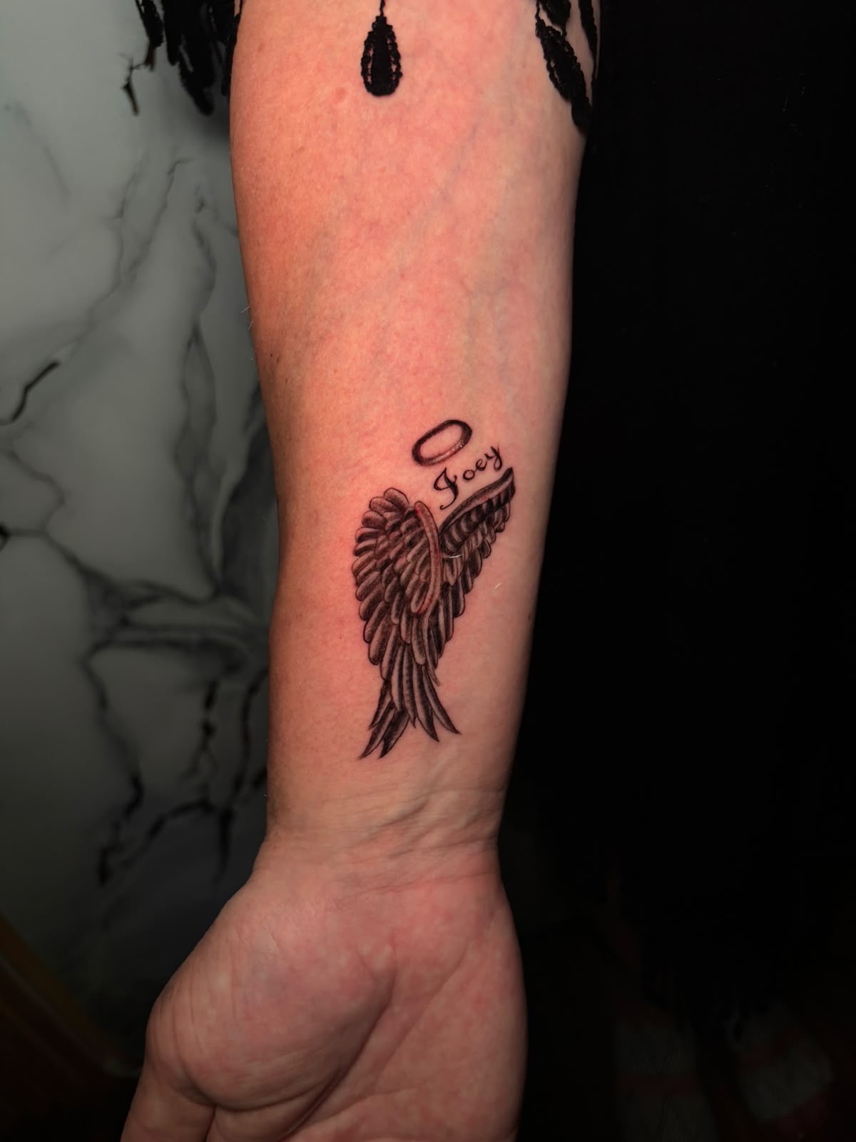 Angel wing and halo memorial tattoo on the forearm