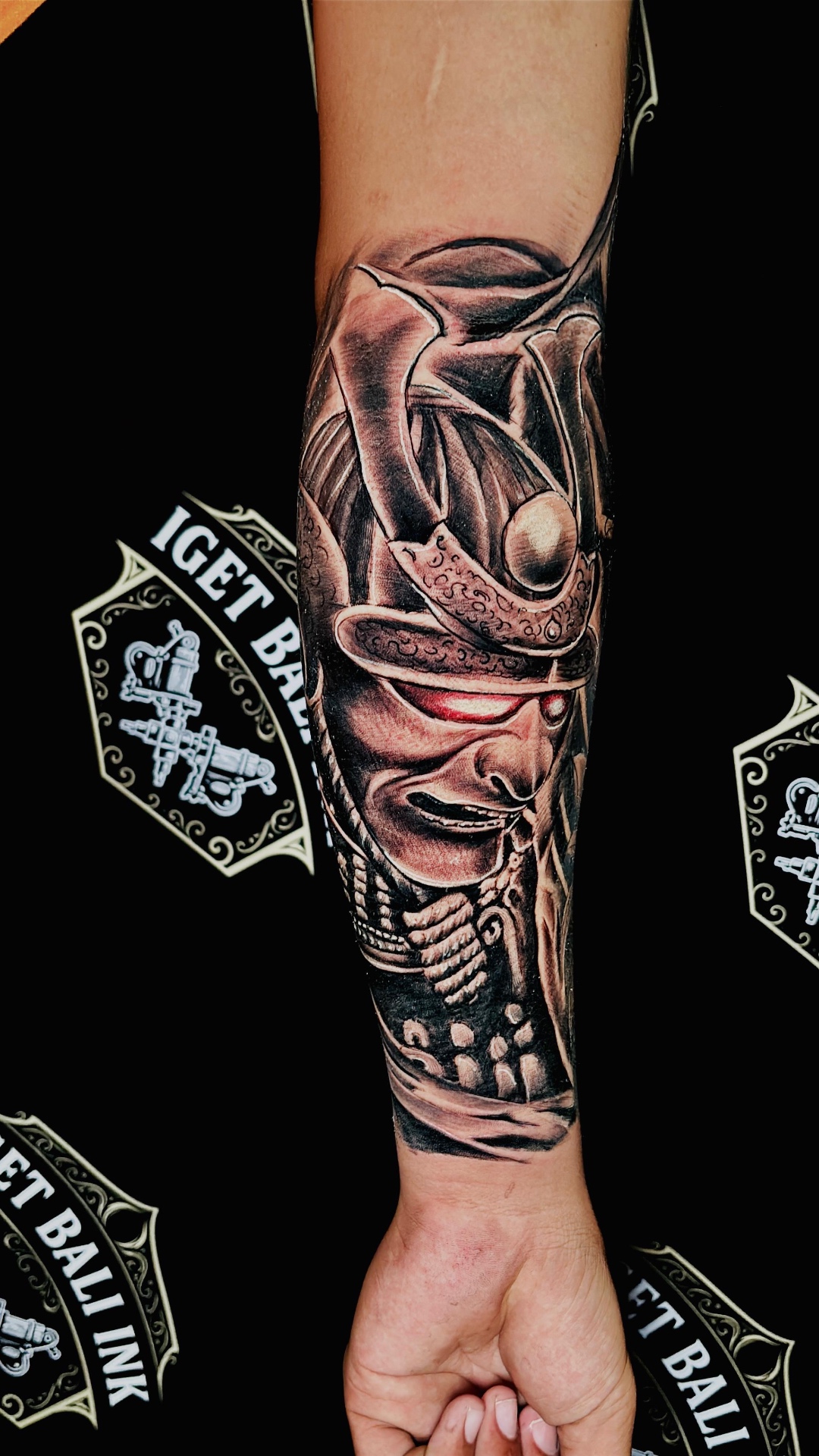 Samurai mask forearm tattoo in black and grey with red eye
