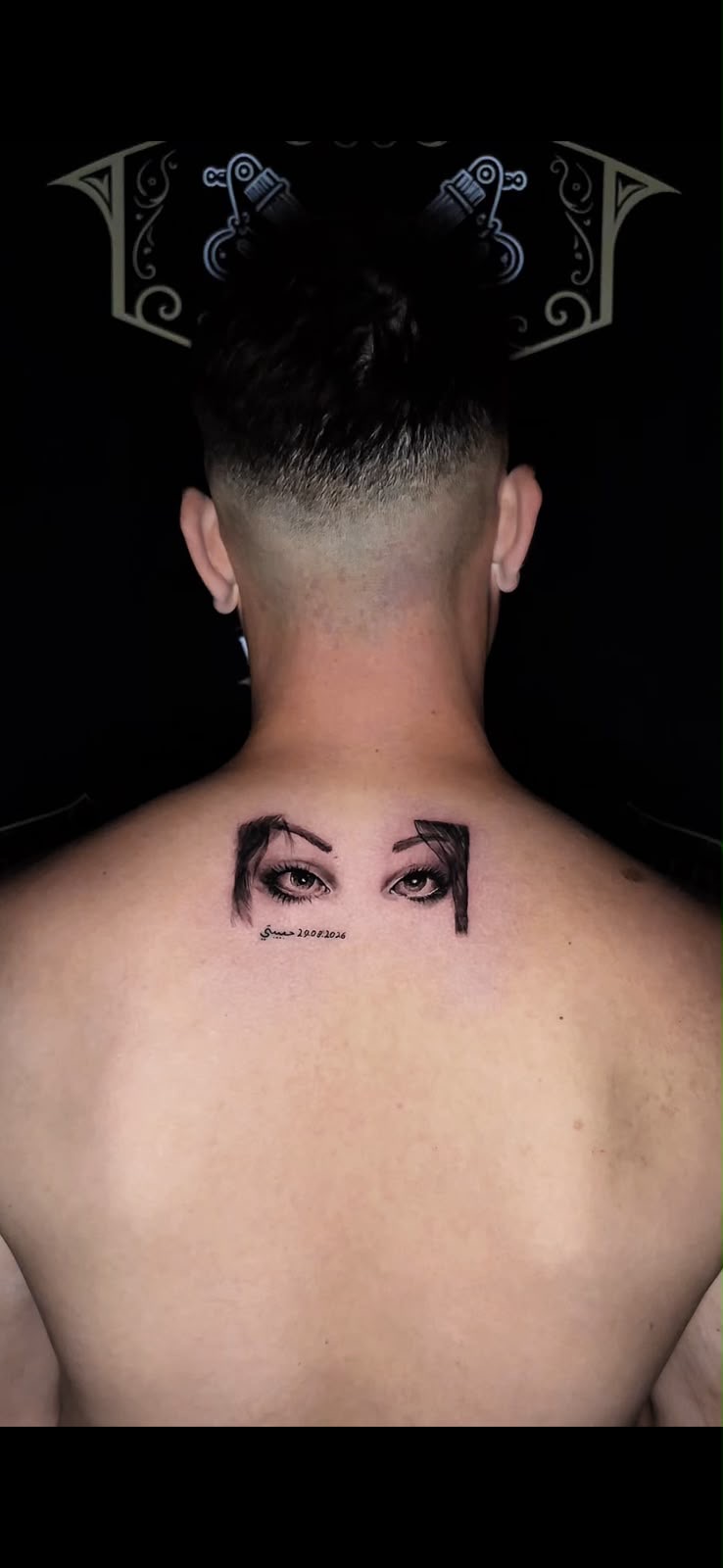 Realistic eyes with Arabic script tattoo on the upper back