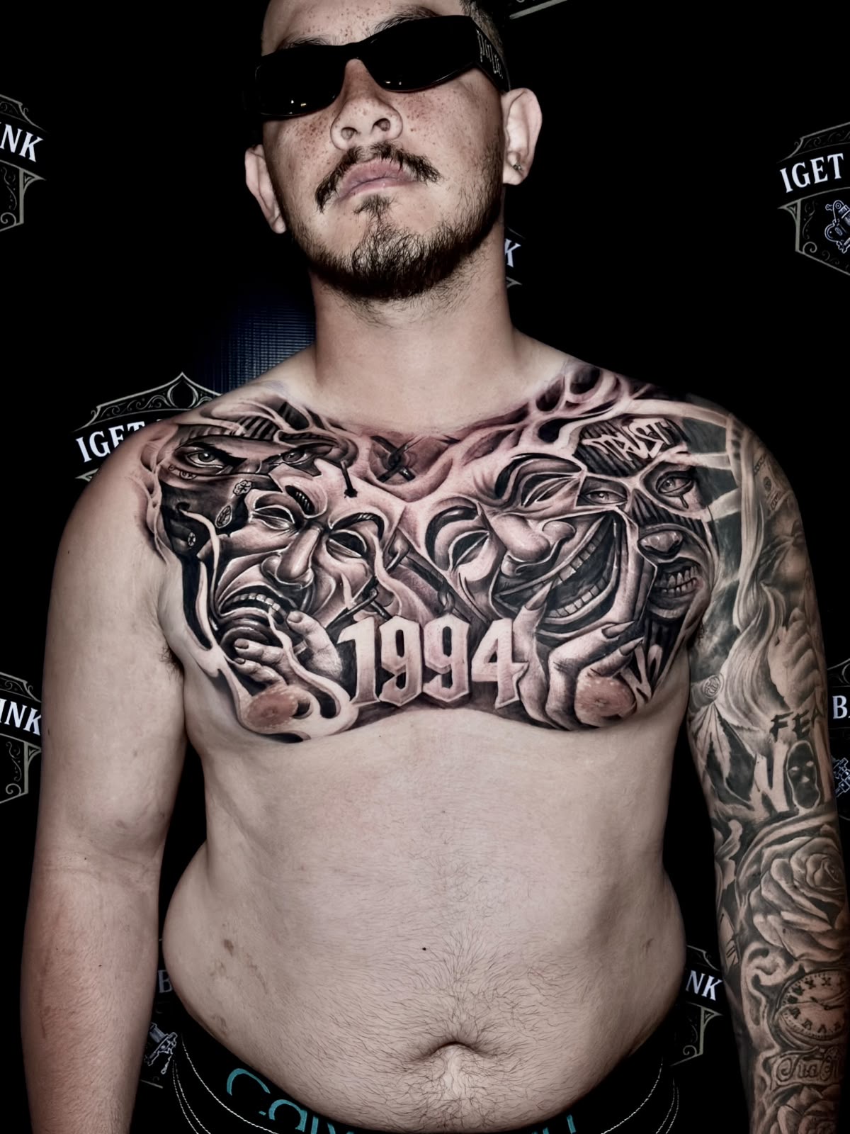Black and grey chicano chest piece with masks and 1994 lettering