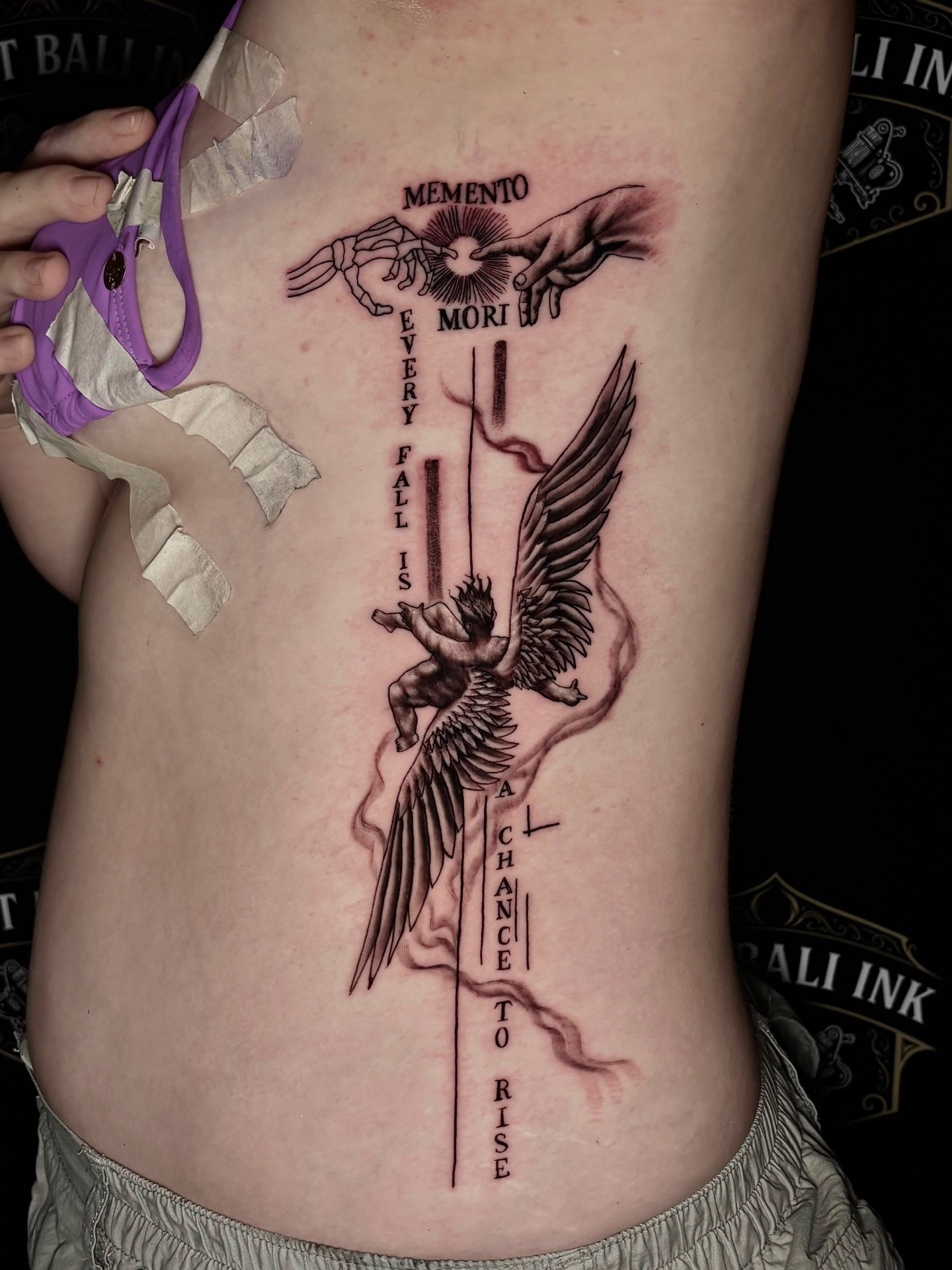 Memento Mori fallen angel rib tattoo in black and grey