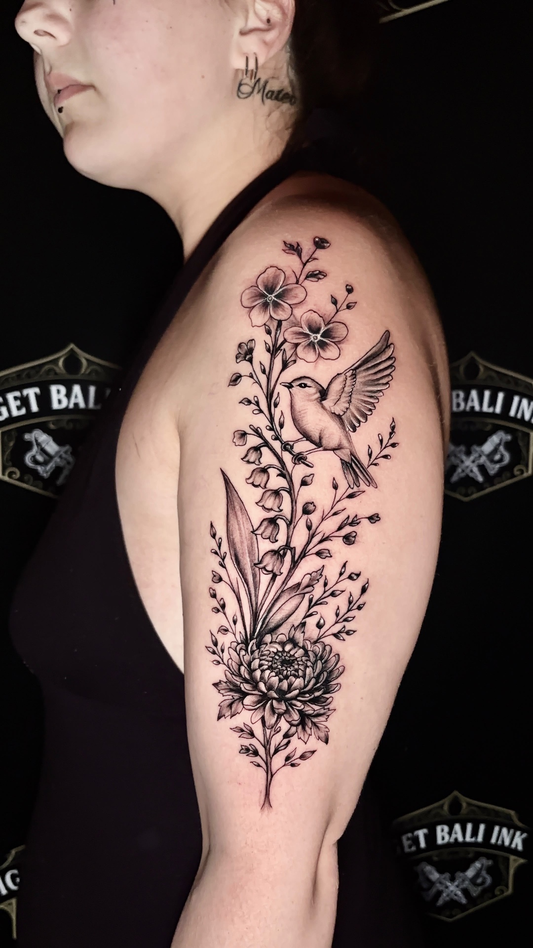 Fine line hummingbird and floral upper arm tattoo
